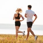 Back view of young fitness man and woman doing jogging sport outdoors